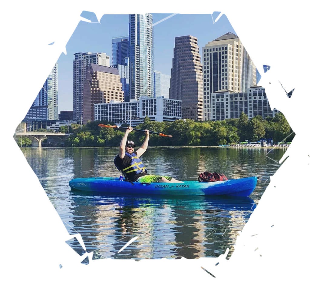 Me kayaking on a bright blue lake in Austin with the city skyline in the background